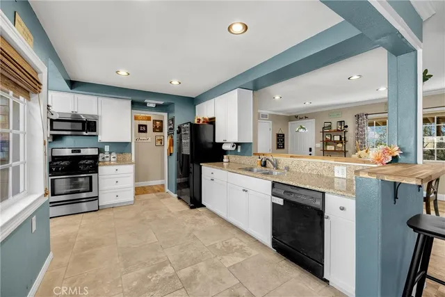 a large kitchen with stainless steel appliances kitchen island granite countertop a refrigerator and a stove top oven