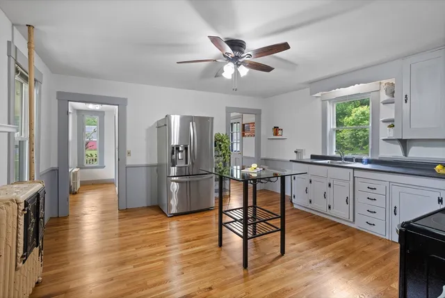 a kitchen with stainless steel appliances a dining table chairs and wooden floor