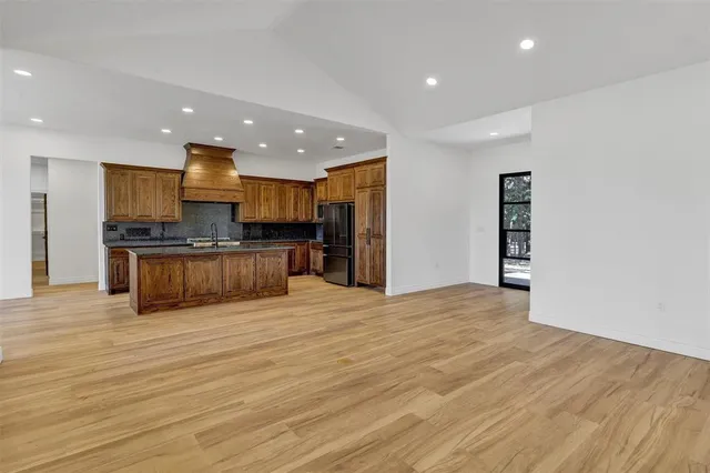 a view of kitchen with kitchen island granite countertop a refrigerator oven a sink and dishwasher with wooden floor