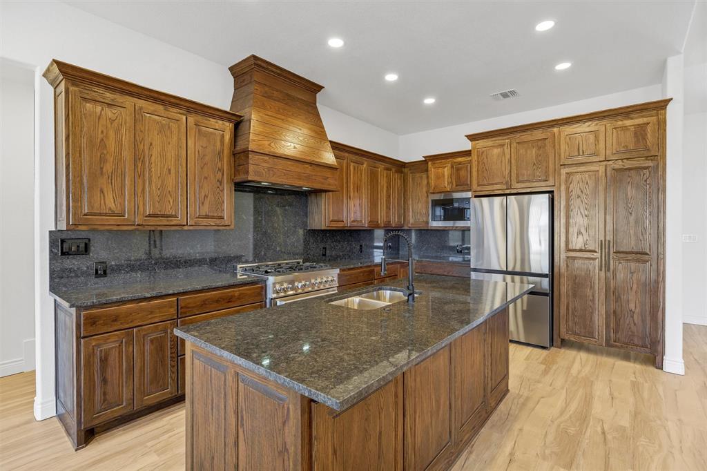 3031 Powell Cemetery Road Tolar, TX 76476 - Photo 14 of 40 a kitchen with stainless steel appliances granite countertop a sink a stove and a refrigerator