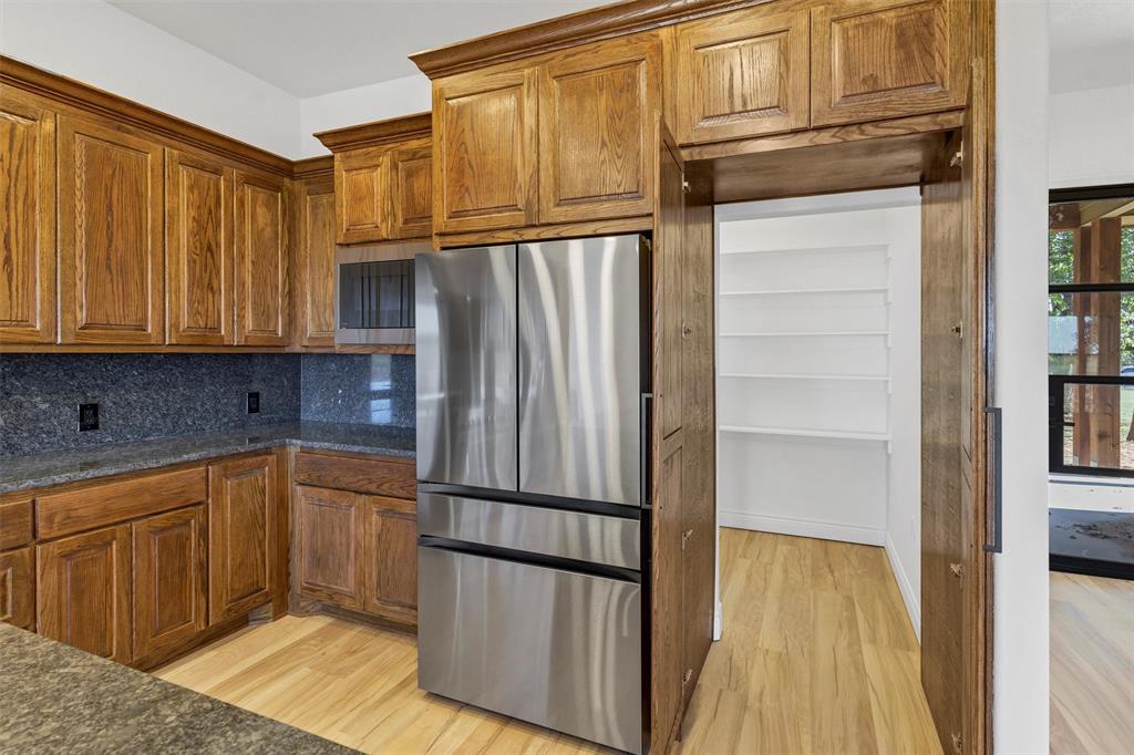 3031 Powell Cemetery Road Tolar, TX 76476 - Photo 16 of 40 a kitchen with stainless steel appliances granite countertop a refrigerator and a stove top oven