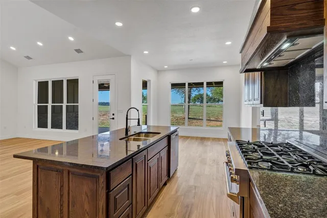 a kitchen with granite countertop a sink stove and cabinets