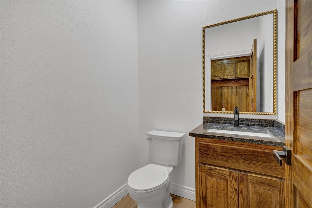 3031 Powell Cemetery Road Tolar, TX 76476 - Photo 22 of 40 a bathroom with a granite countertop toilet sink and mirror