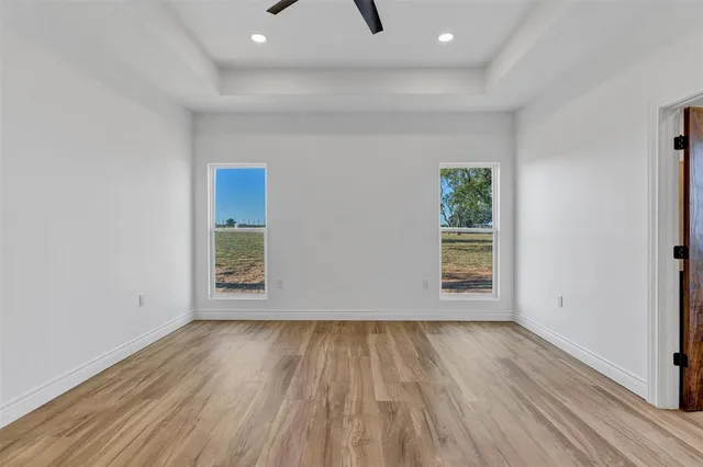 an empty room with wooden floor and windows