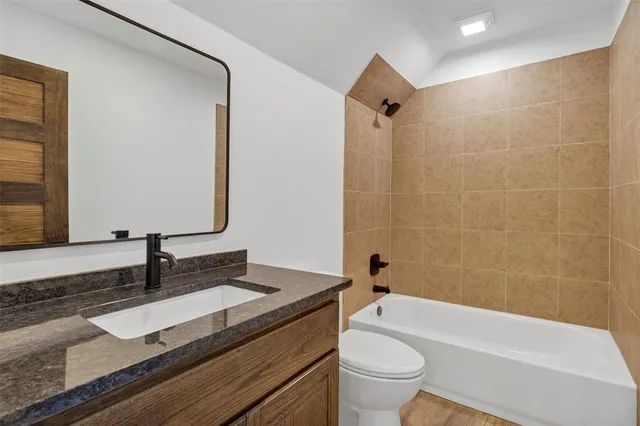 a bathroom with a granite countertop sink a toilet and a bathtub