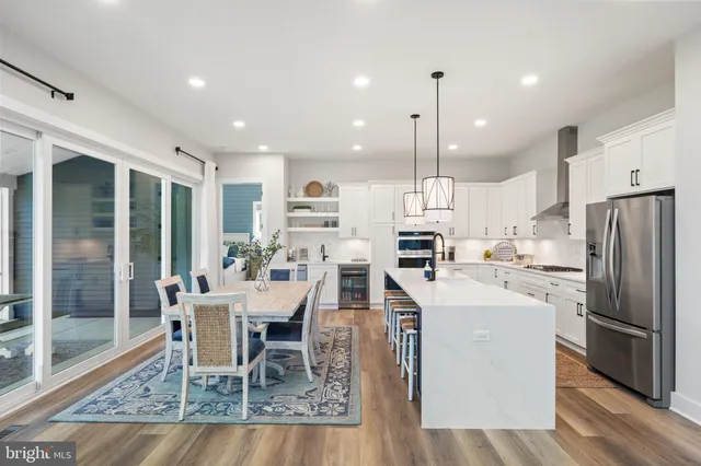 a dining room with stainless steel appliances kitchen island granite countertop a dining table chairs and a refrigerator