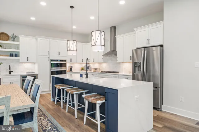 a kitchen with stainless steel appliances granite countertop a sink a stove a refrigerator and island with wooden floor