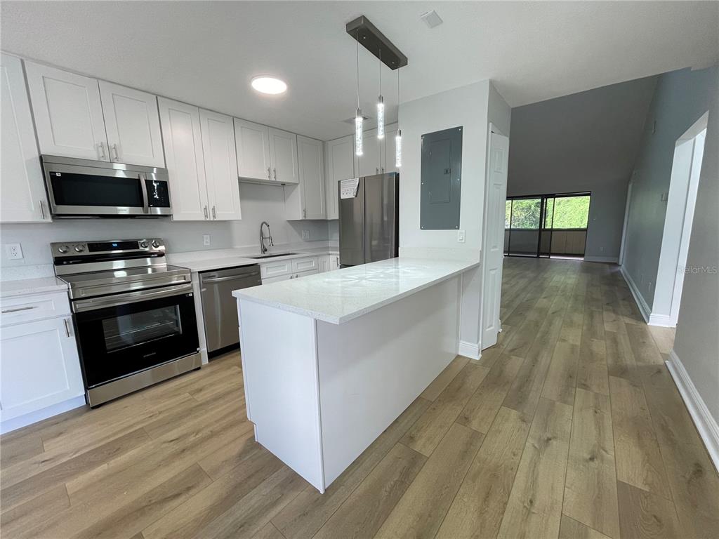 5395 Vineland Road, Unit S Orlando, FL 32811 - Photo 8 of 30 a white kitchen with wooden floor and stainless steel appliances