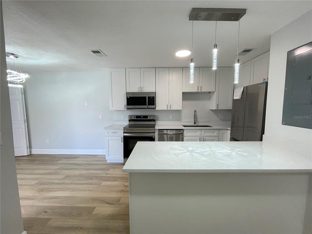 5395 Vineland Road, Unit S Orlando, FL 32811 - Photo 9 of 30 a kitchen with stainless steel appliances kitchen island a refrigerator sink and cabinets