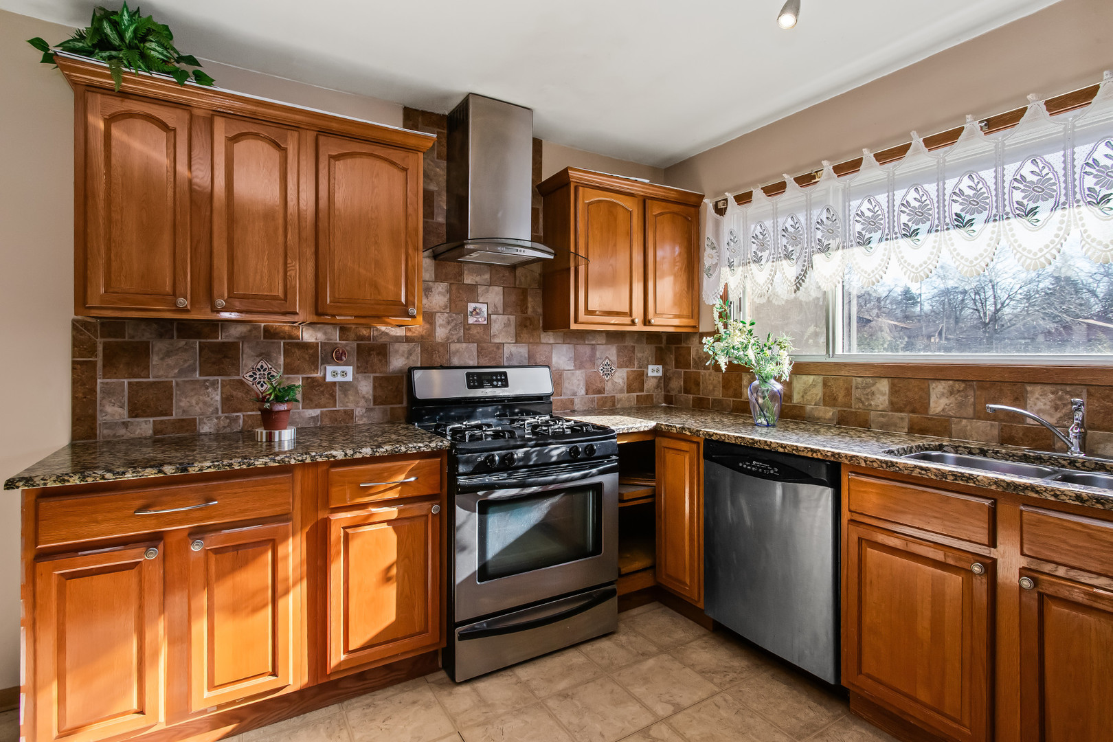 134 Virginia Court Streamwood, IL 60107 - Photo 5 of 25 a kitchen with granite countertop wooden cabinets stainless steel appliances and a large window
