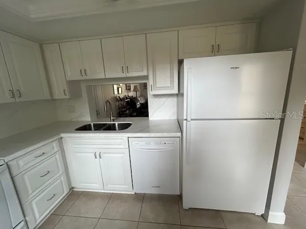 a kitchen with white cabinets and white appliances