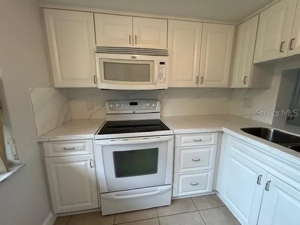 a kitchen with white cabinets and white appliances