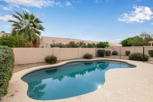 a view of a house with pool fire pit a chairs and wooden fence