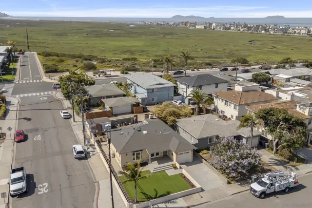 an aerial view of ocean and residential houses with outdoor space