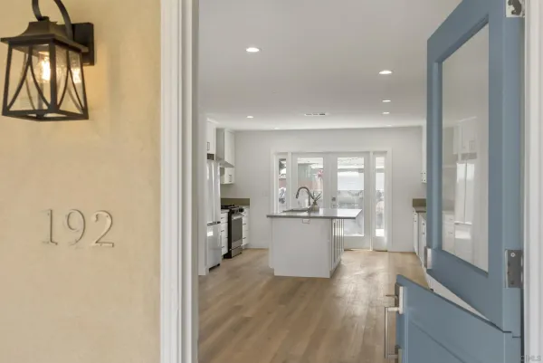 a open kitchen with white cabinets and wooden floor