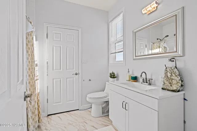 a bathroom with a granite countertop toilet a sink and a mirror