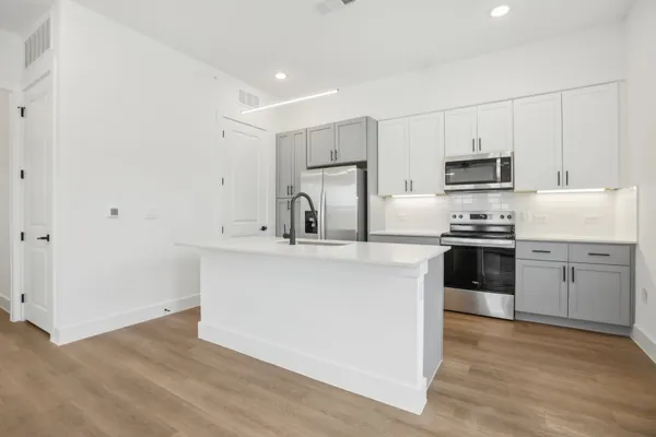 a kitchen with cabinets stainless steel appliances and wooden floor