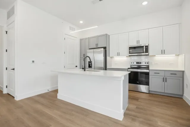 a kitchen with cabinets stainless steel appliances and wooden floor