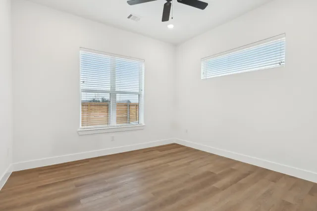 an empty room with a window and a ceiling fan