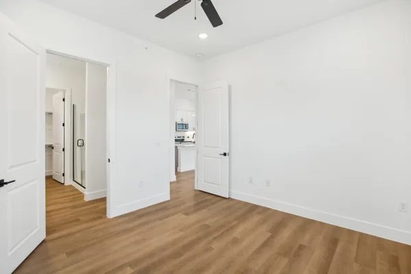 an empty room with wooden floor and ceiling fan