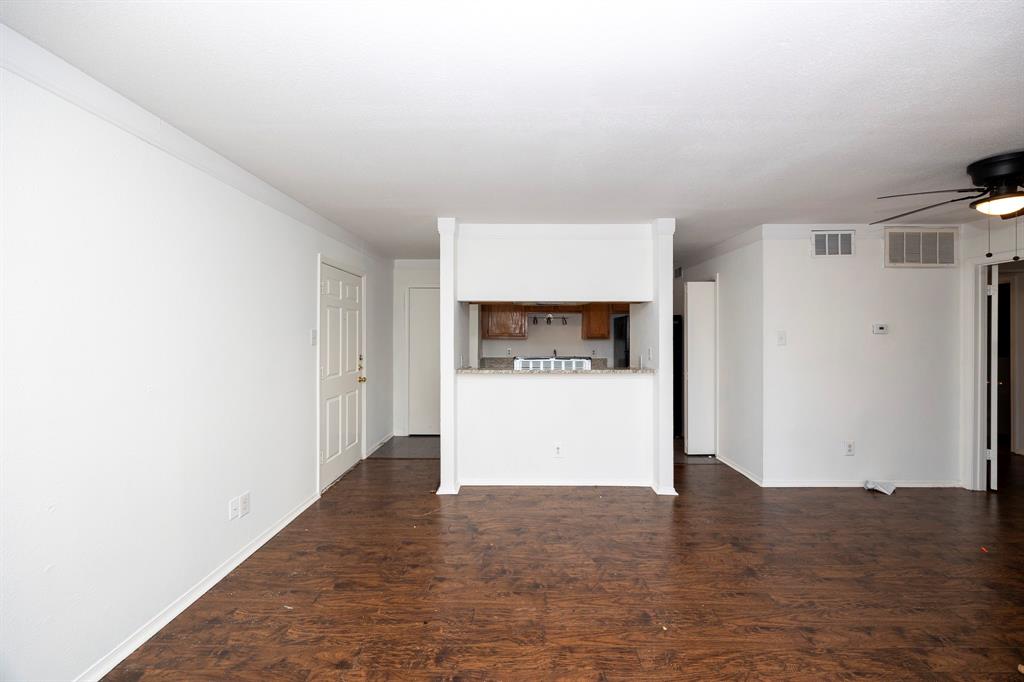 18333 Roehampton Drive, Unit 825 Dallas, TX 75252 - Photo 4 of 23 Wood-finish flooring throughout, white painted walls, and a built-in breakfast bar with a light-toned countertop