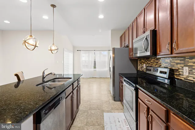 a kitchen with granite countertop stainless steel appliances a sink stove and cabinets