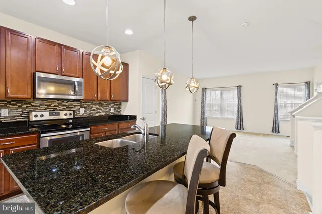 a kitchen with granite countertop a stove a sink a dining table and chairs