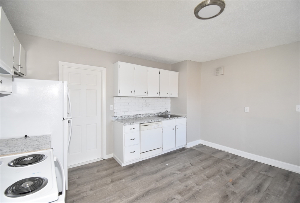 51-53 Eloise Street Springfield, MA 01118 - Photo 10 of 20 a kitchen with granite countertop a stove a sink and white cabinets