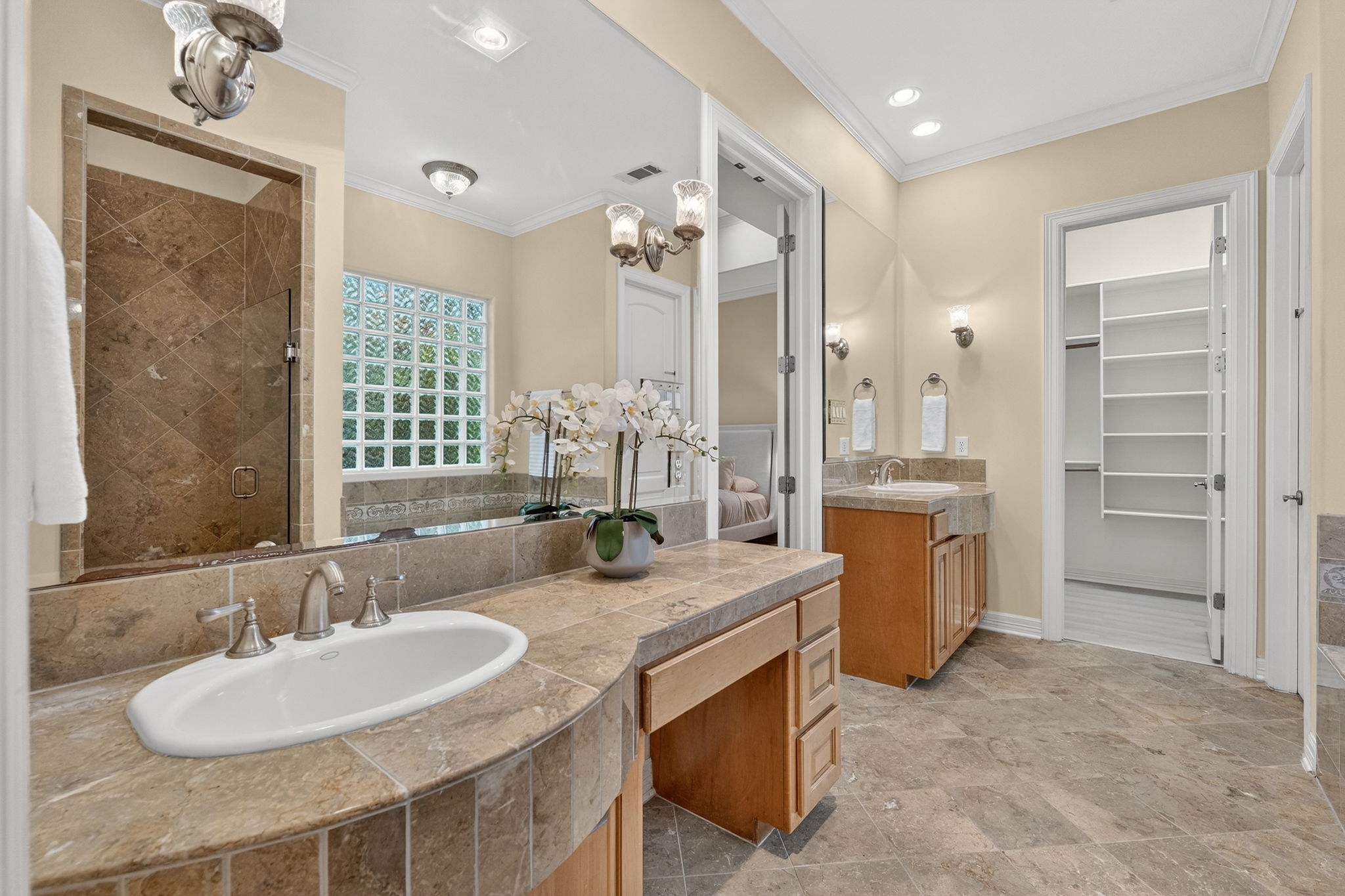 4110 Bunny Run, Unit 3 Austin, TX 78746 - Photo 16 of 35 Bathroom featuring a large vanity with a white oval sink, a separate vanity with a rectangular sink, a glass block window, and a walk-in shower with tiled walls