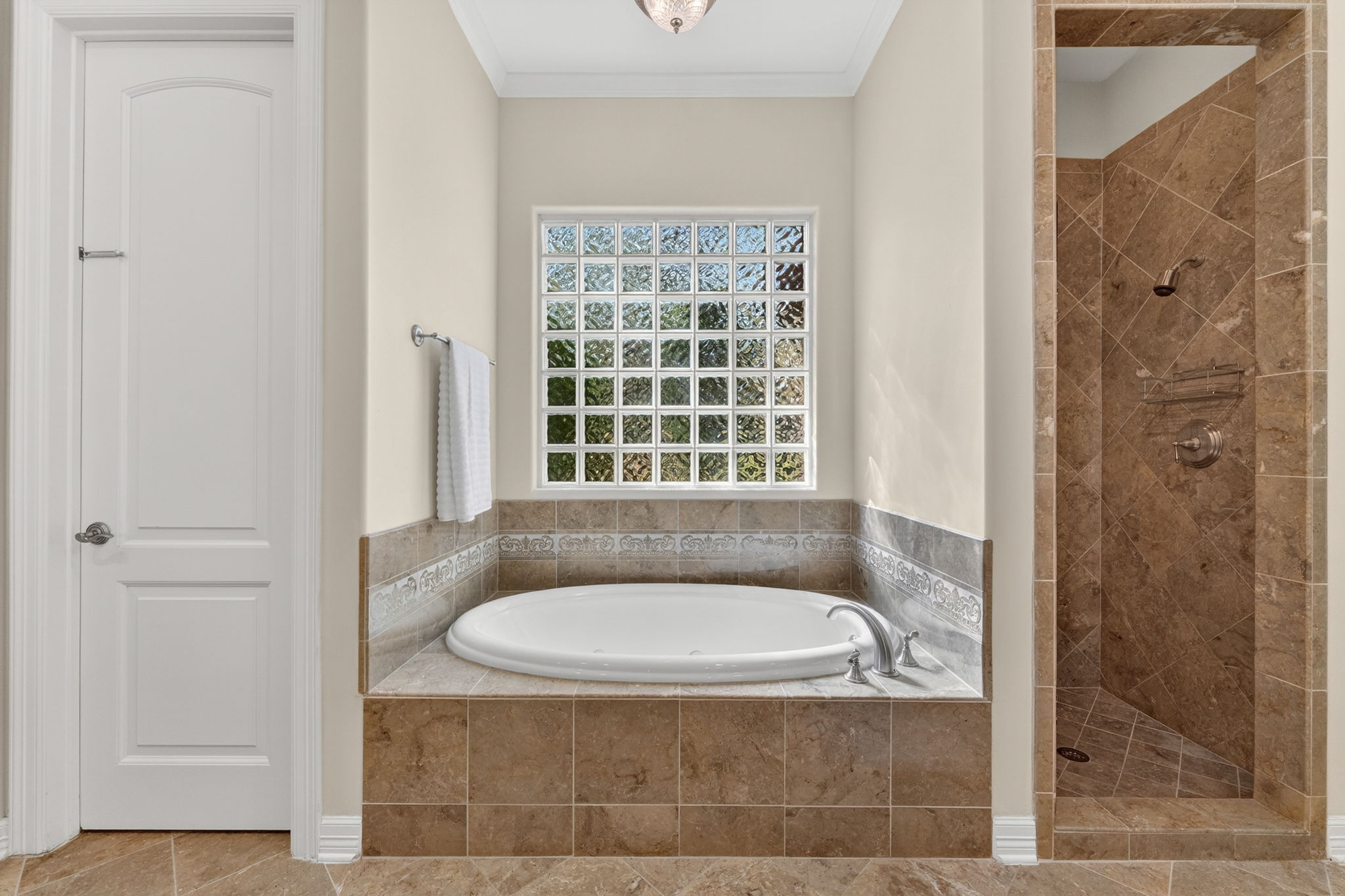 4110 Bunny Run, Unit 3 Austin, TX 78746 - Photo 17 of 35 This bathroom features a built-in tub with tile surround, a glass block window, and a tiled walk-in shower