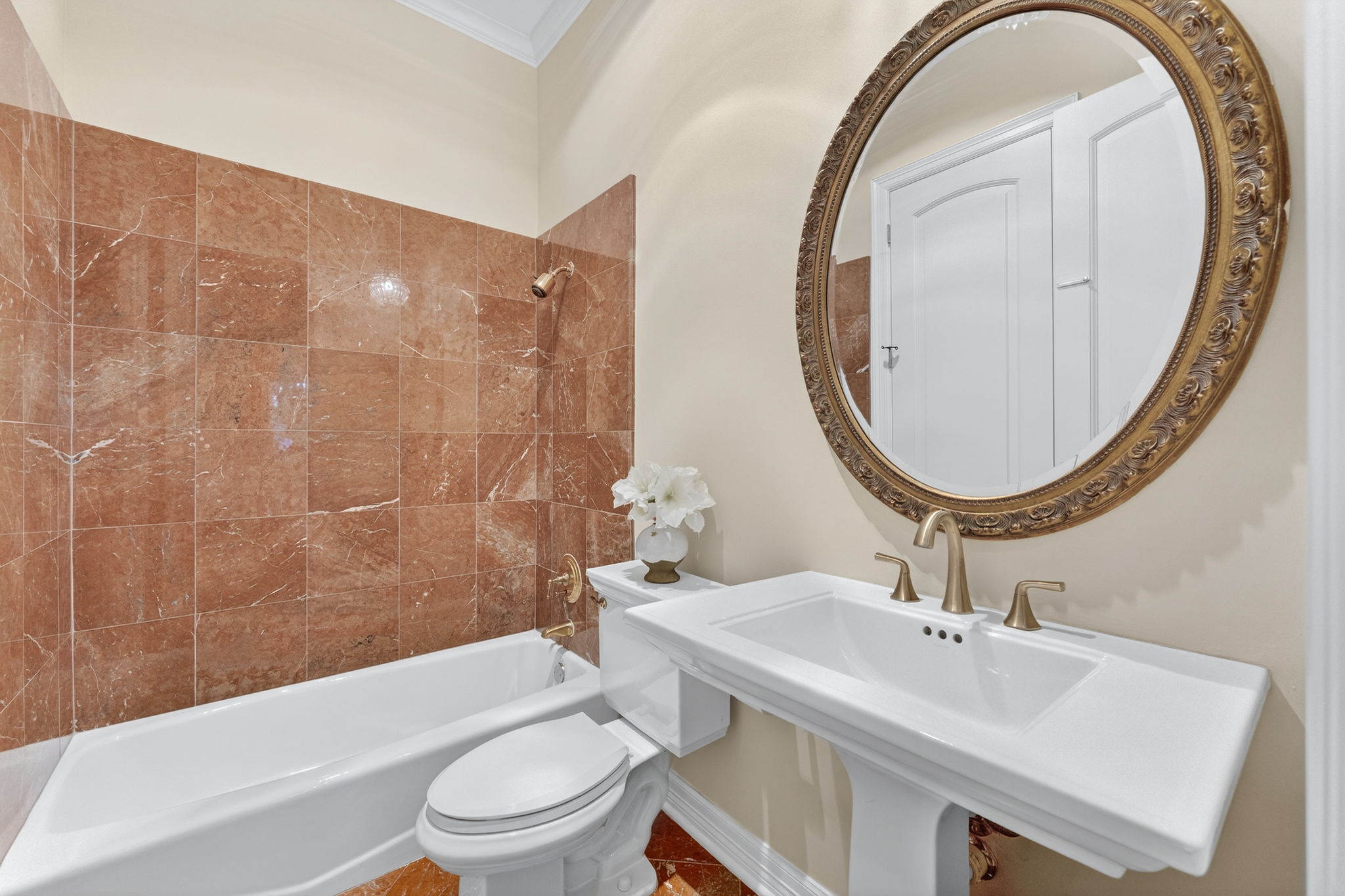 4110 Bunny Run, Unit 3 Austin, TX 78746 - Photo 19 of 35 This bathroom features a pedestal sink with a gold-toned faucet, a large ornate gold-framed mirror, and a bathtub with a shower