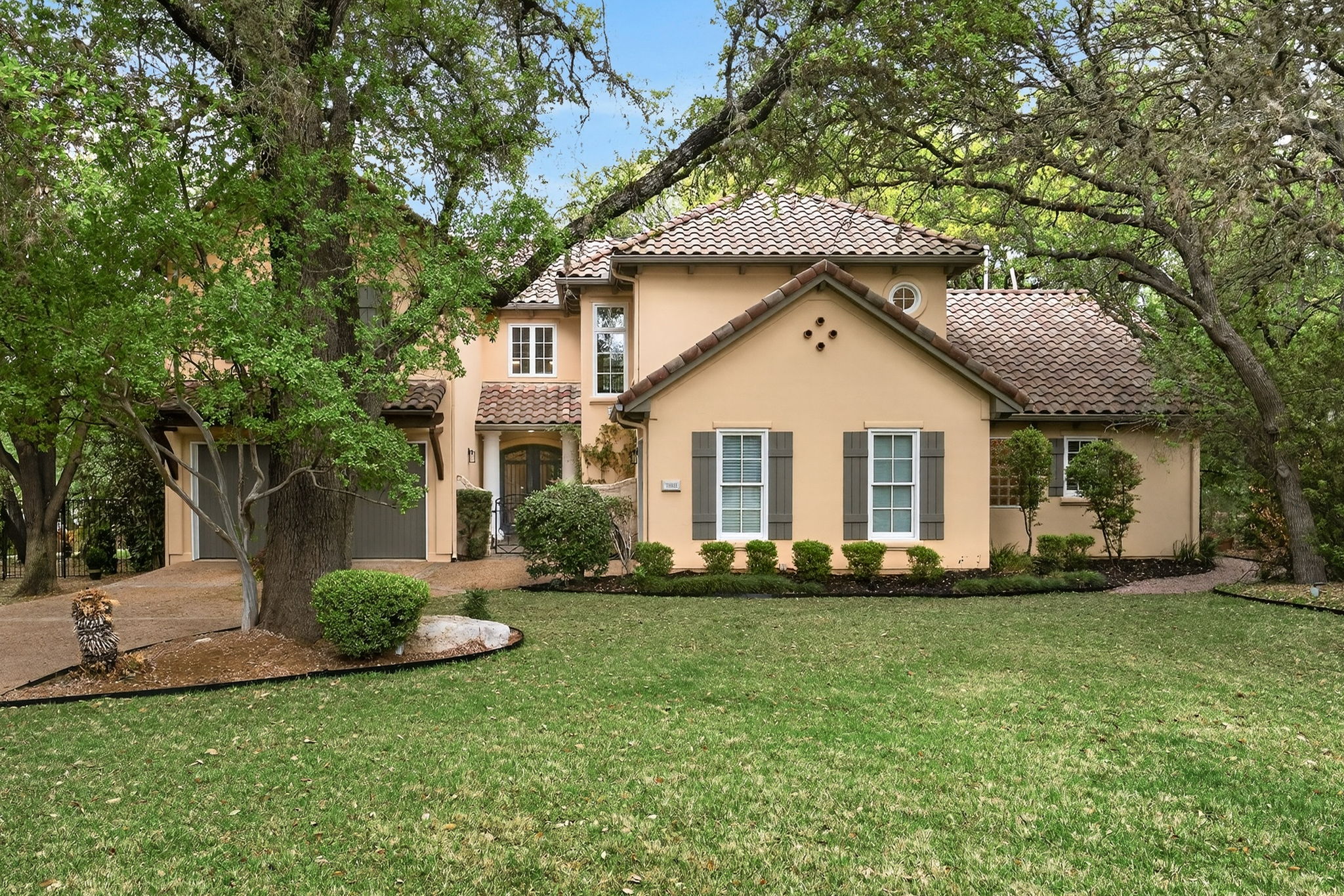 4110 Bunny Run, Unit 3 Austin, TX 78746 - Photo 2 of 35 The property features a stucco exterior with a tiled roof, surrounded by mature trees