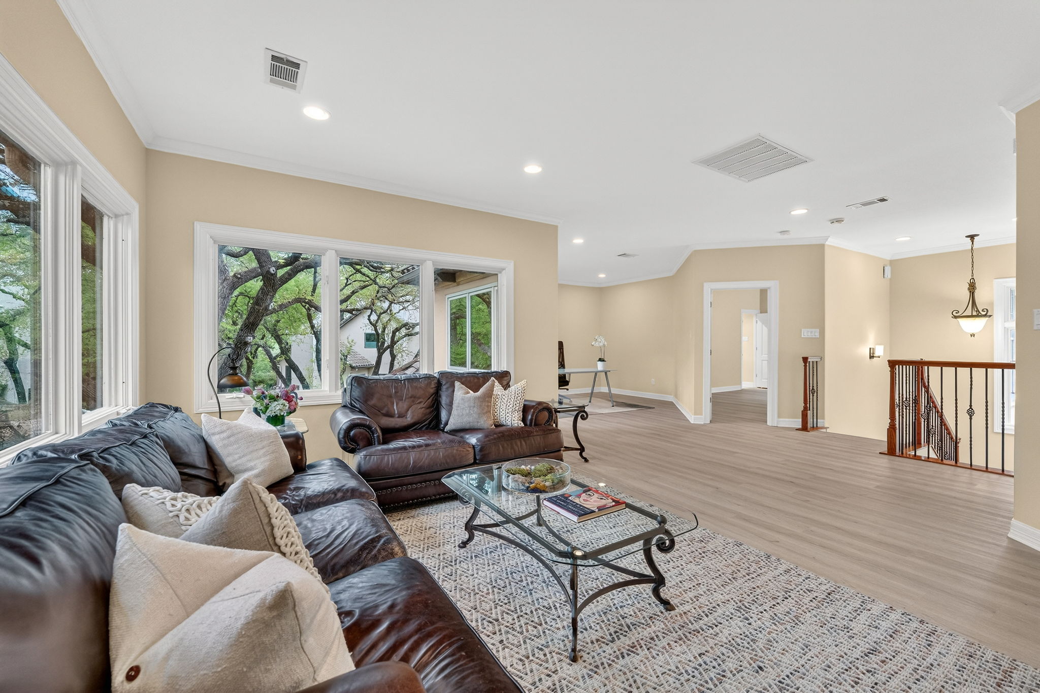 4110 Bunny Run, Unit 3 Austin, TX 78746 - Photo 21 of 35 Living room featuring light-colored walls, large windows offering views of lush greenery, and light-toned flooring