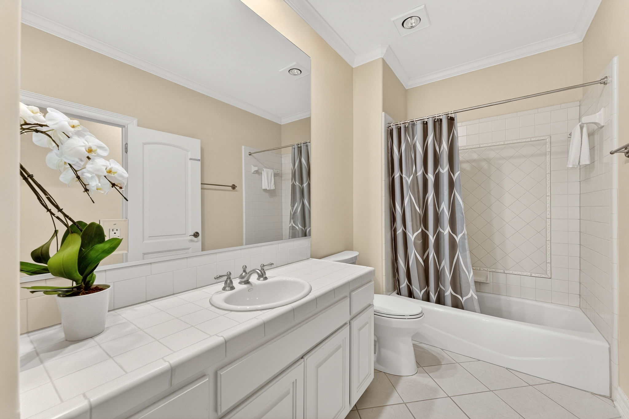 4110 Bunny Run, Unit 3 Austin, TX 78746 - Photo 26 of 35 This bathroom features a spacious vanity with a tiled countertop and an integrated sink, complemented by a large mirror