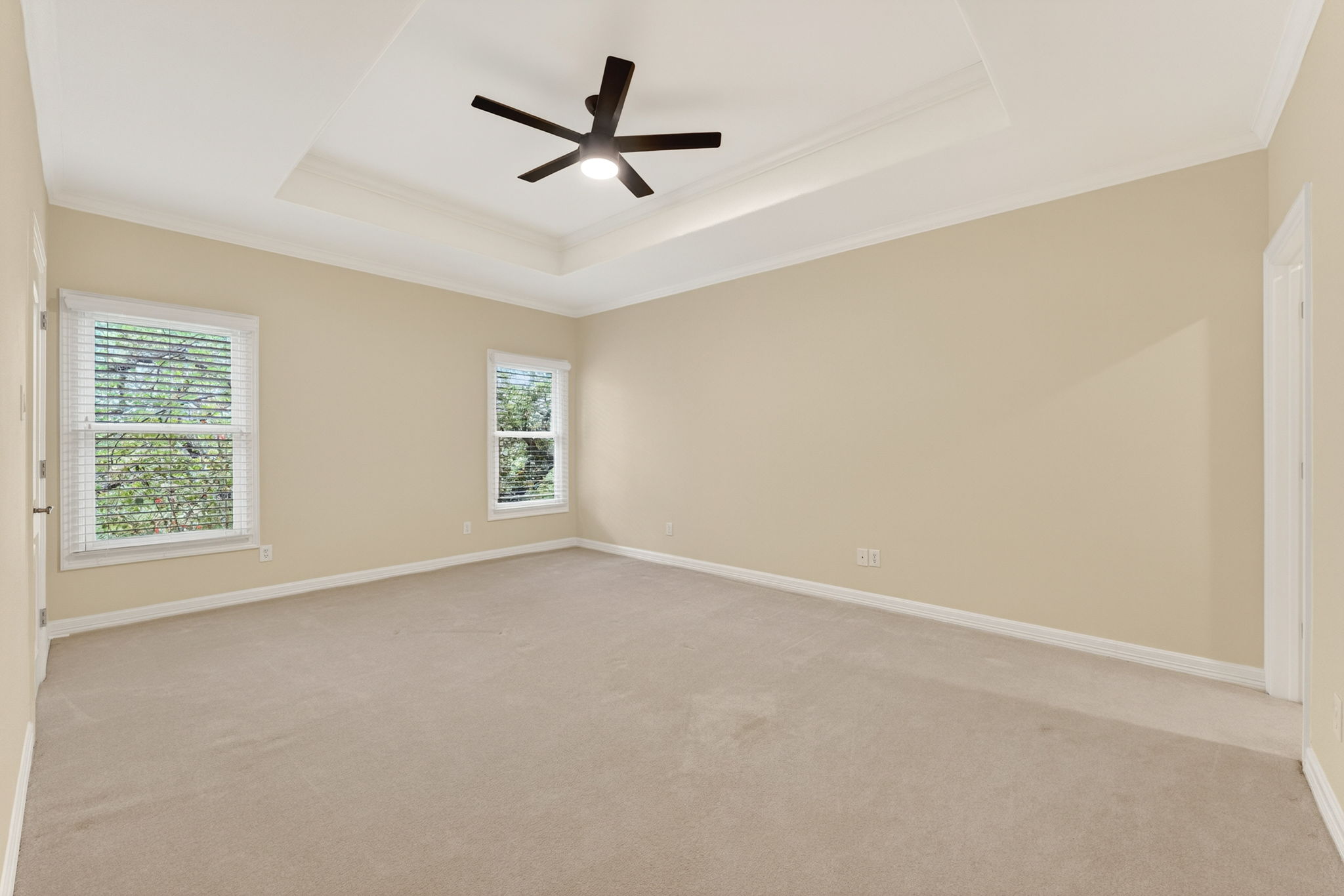 4110 Bunny Run, Unit 3 Austin, TX 78746 - Photo 27 of 35 Spacious room featuring neutral carpet, two windows with blinds, and a tray ceiling with a ceiling fan