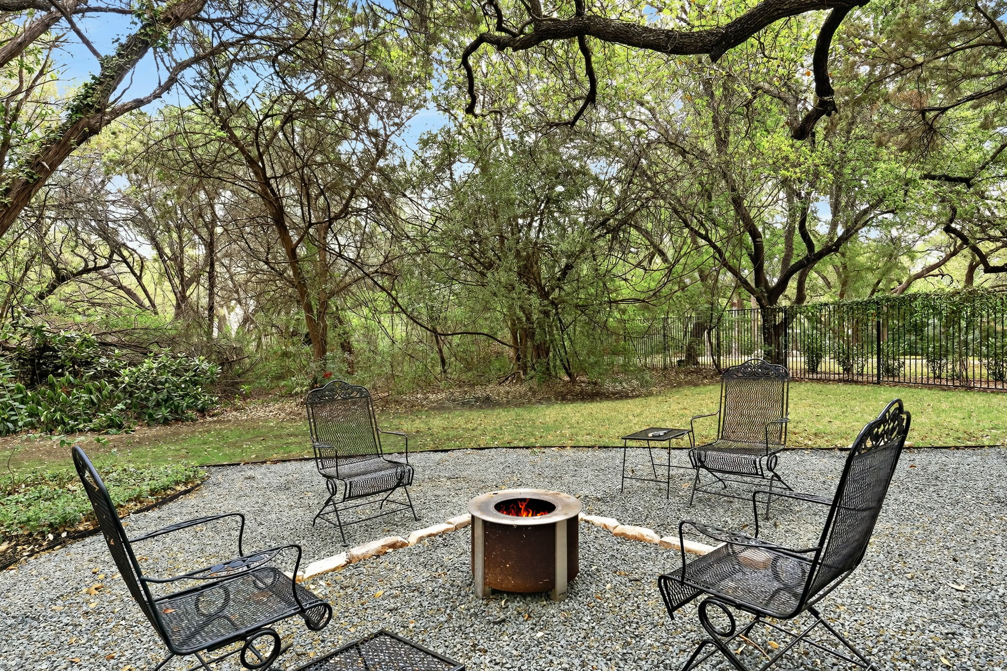 4110 Bunny Run, Unit 3 Austin, TX 78746 - Photo 32 of 35 The property features an outdoor entertaining area with a fire pit, surrounded by gravel paving and mature trees