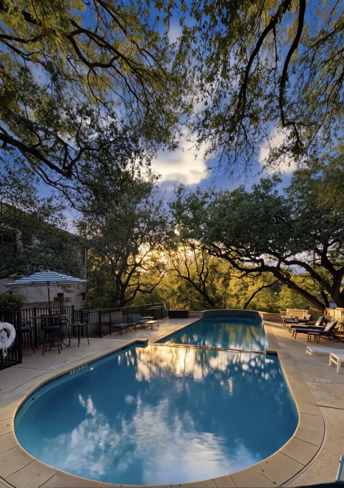 4110 Bunny Run, Unit 3 Austin, TX 78746 - Photo 35 of 35 The property features an outdoor swimming pool with surrounding lounge chairs and a patio area with a table and chairs