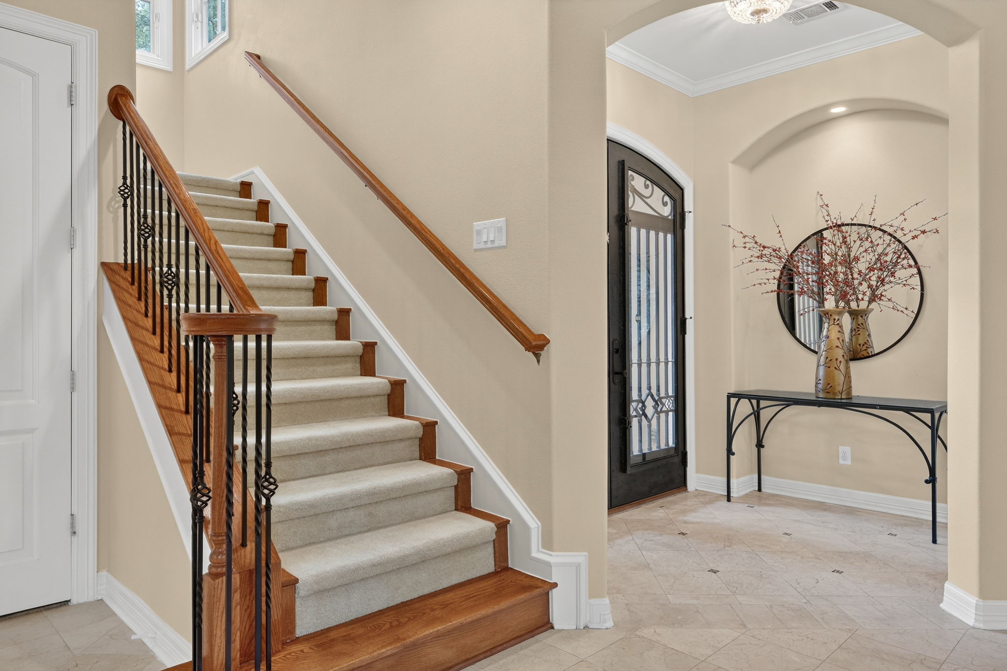 4110 Bunny Run, Unit 3 Austin, TX 78746 - Photo 4 of 35 The property features a grand staircase with wooden treads, carpeted risers, and a wrought iron balustrade