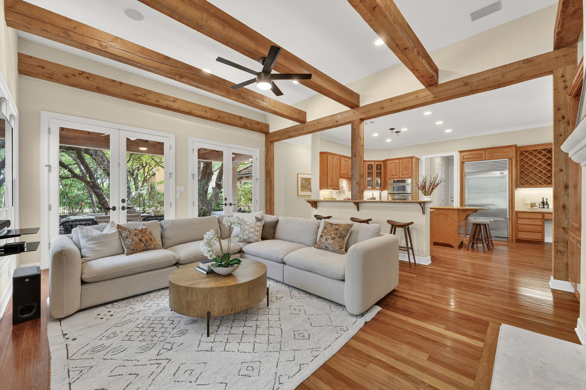 4110 Bunny Run, Unit 3 Austin, TX 78746 - Photo 7 of 35 Spacious living area featuring exposed wooden beams, hardwood flooring, and direct access to an outdoor area through glass doors