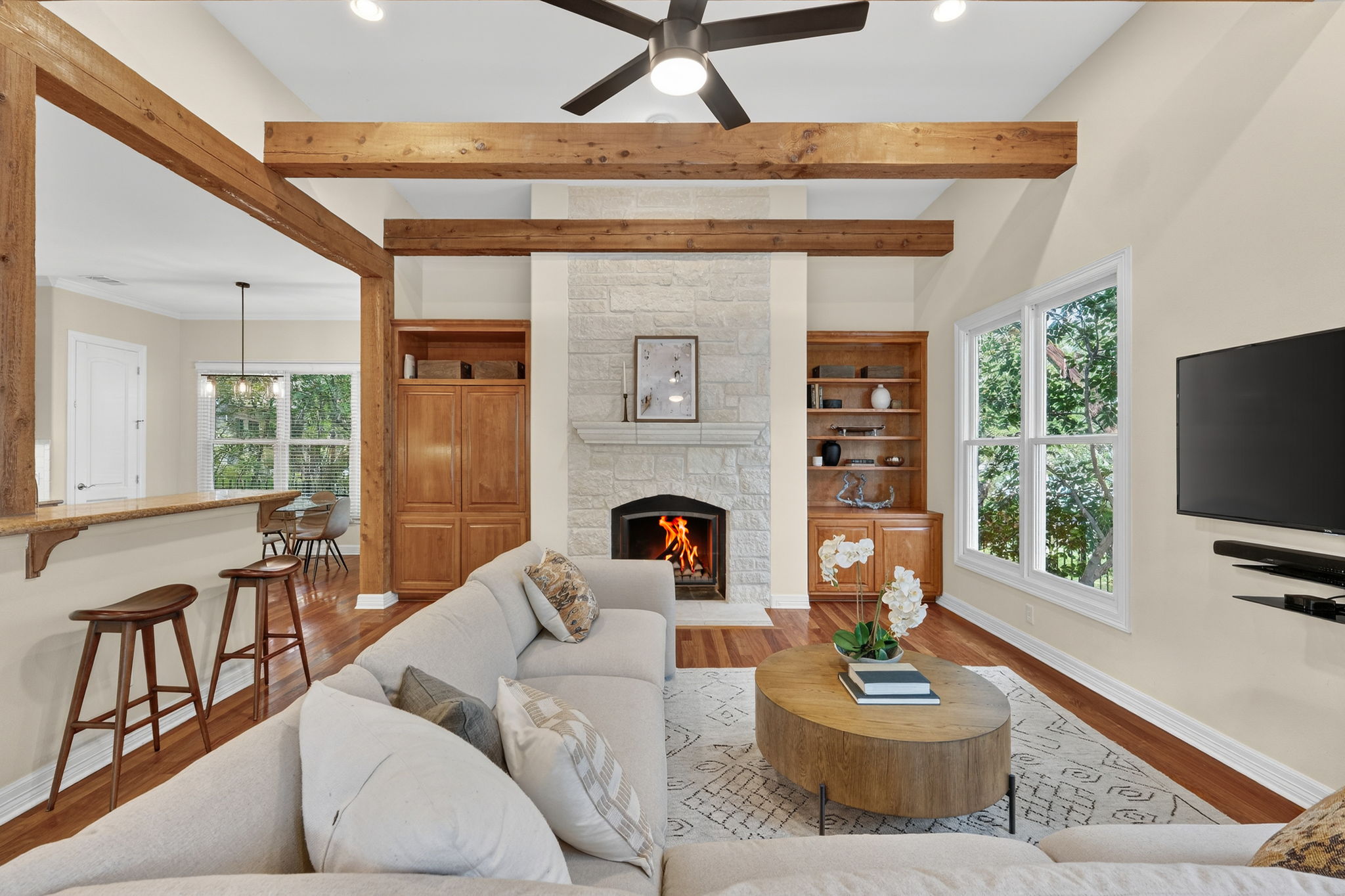 4110 Bunny Run, Unit 3 Austin, TX 78746 - Photo 8 of 35 Living area featuring a stone fireplace, exposed wood beams, and hardwood floors
