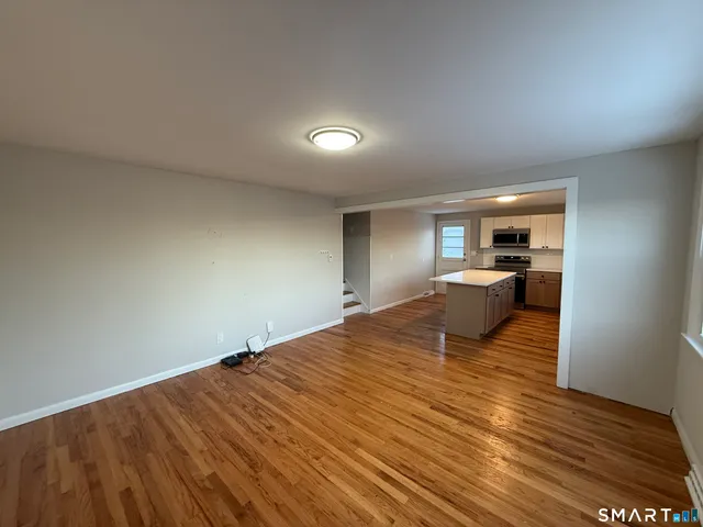 a view of a room with wooden floor kitchen view and a window