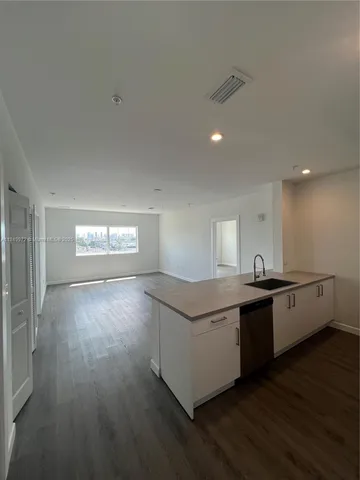 a large kitchen with stainless steel appliances a large counter top and wooden floor