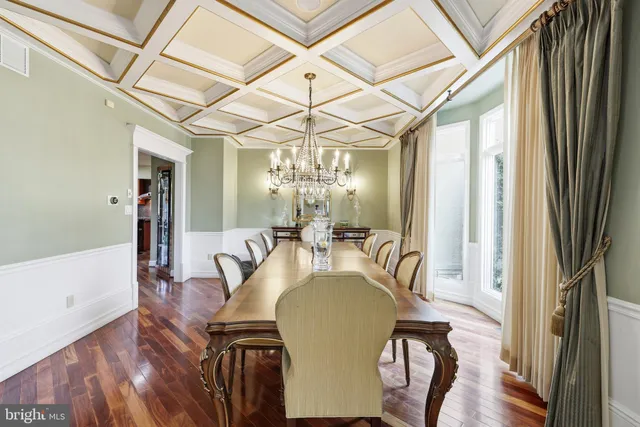 a dining room with wooden floor a chandelier a wooden table and chairs