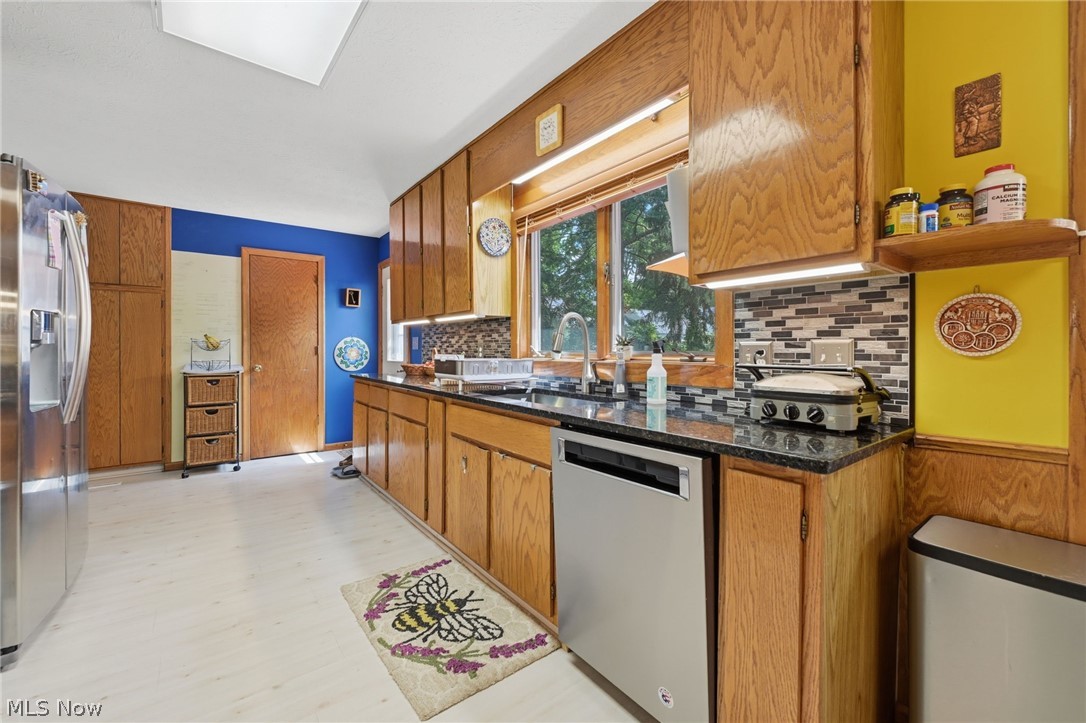 1499 Morris Road Kent, OH 44240 - Photo 23 of 41 Kitchen featuring wood cabinetry, stainless steel appliances, dark granite countertops, and a mosaic tile backsplash