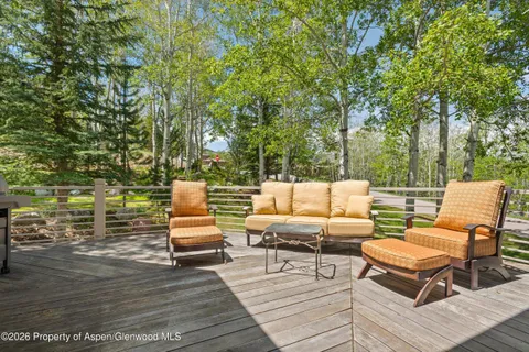 a view of a patio with couches table and chairs with wooden floor and fence