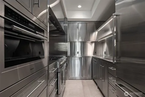 a kitchen with stainless steel appliances kitchen island granite countertop a table chairs sink and cabinets