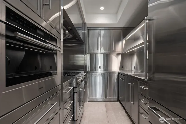 a kitchen with stainless steel appliances kitchen island granite countertop a table chairs sink and cabinets