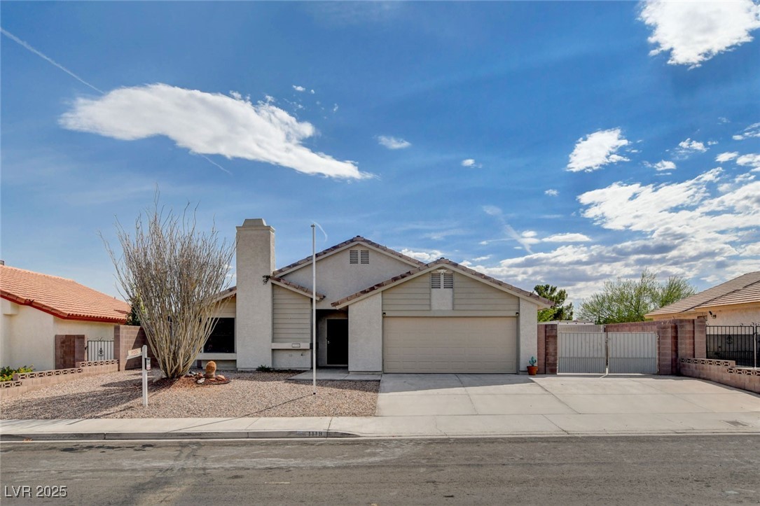 View of front of home with a gate, a garage, driveway, and a chimney