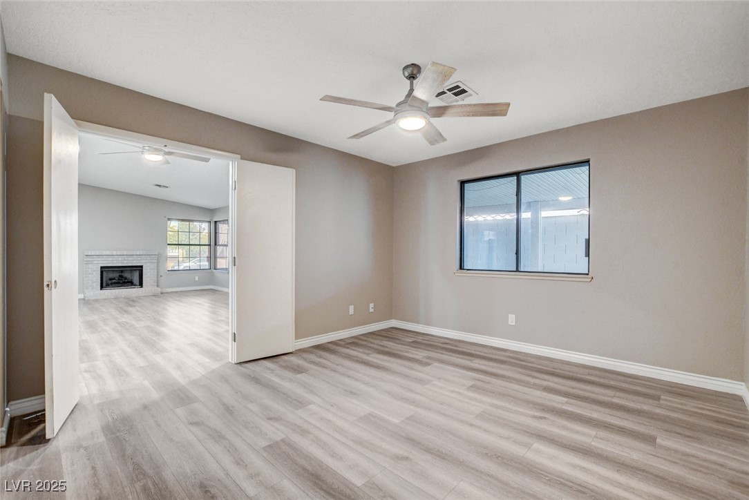 1118 Olmo Way Boulder City, NV 89005 - Photo 14 of 45 Empty room featuring light wood finished floors, a ceiling fan, and a fireplace