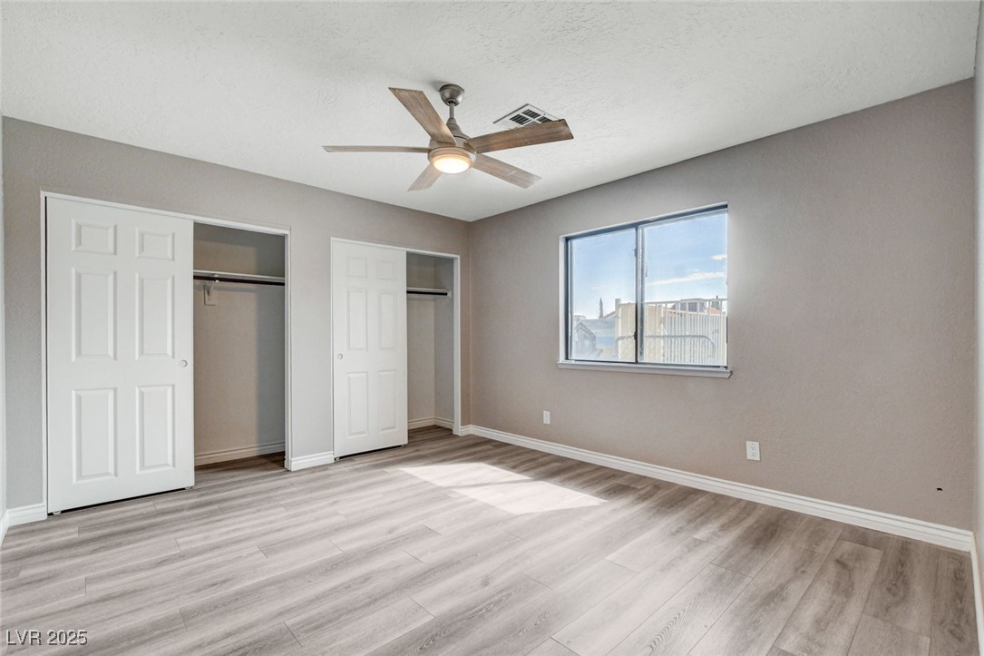 1118 Olmo Way Boulder City, NV 89005 - Photo 16 of 45 Unfurnished bedroom with multiple closets, a textured ceiling, ceiling fan, and light wood-type flooring
